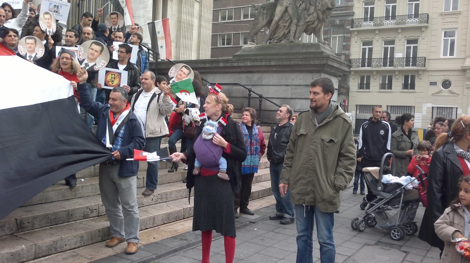علم الجزائر ورضيع يحمل علم سوريا في تجمع مؤيد لسوريا في بلجيكا
